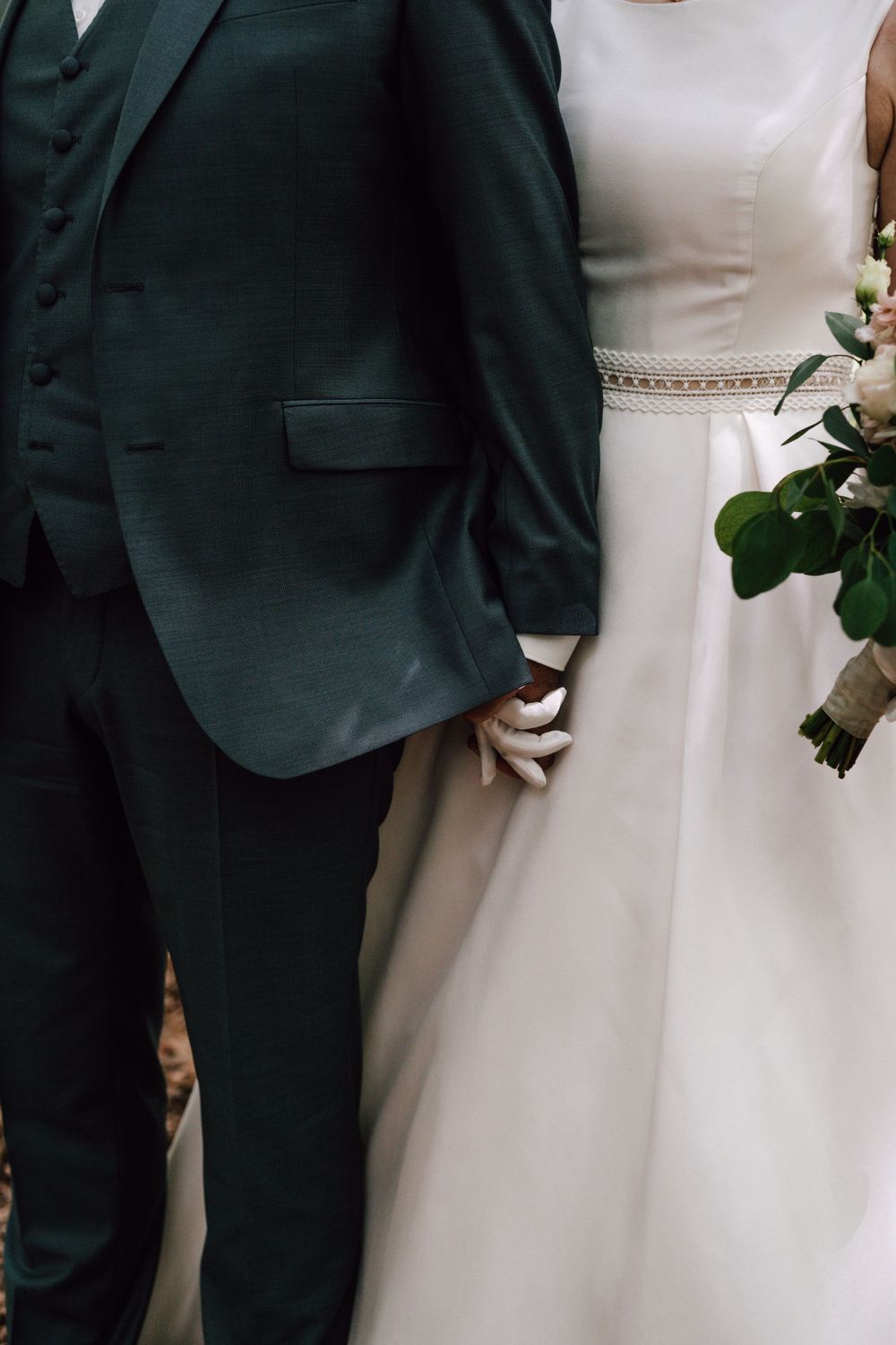 Close-up details of wedding attire showing black suit and white dress.
