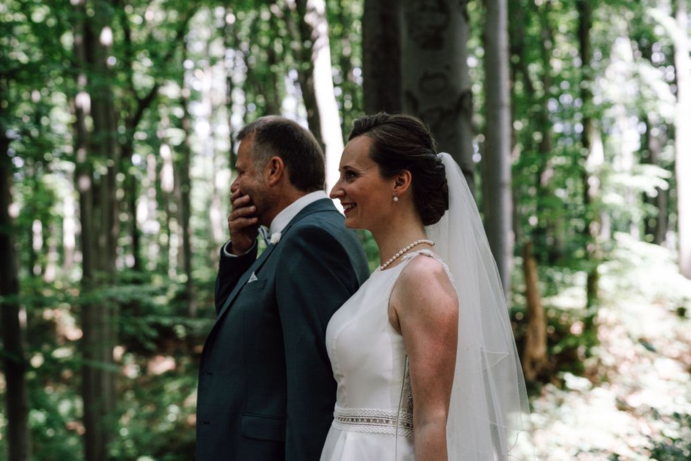 Wedding couple shares intimate moments in a sunlit forest clearing.