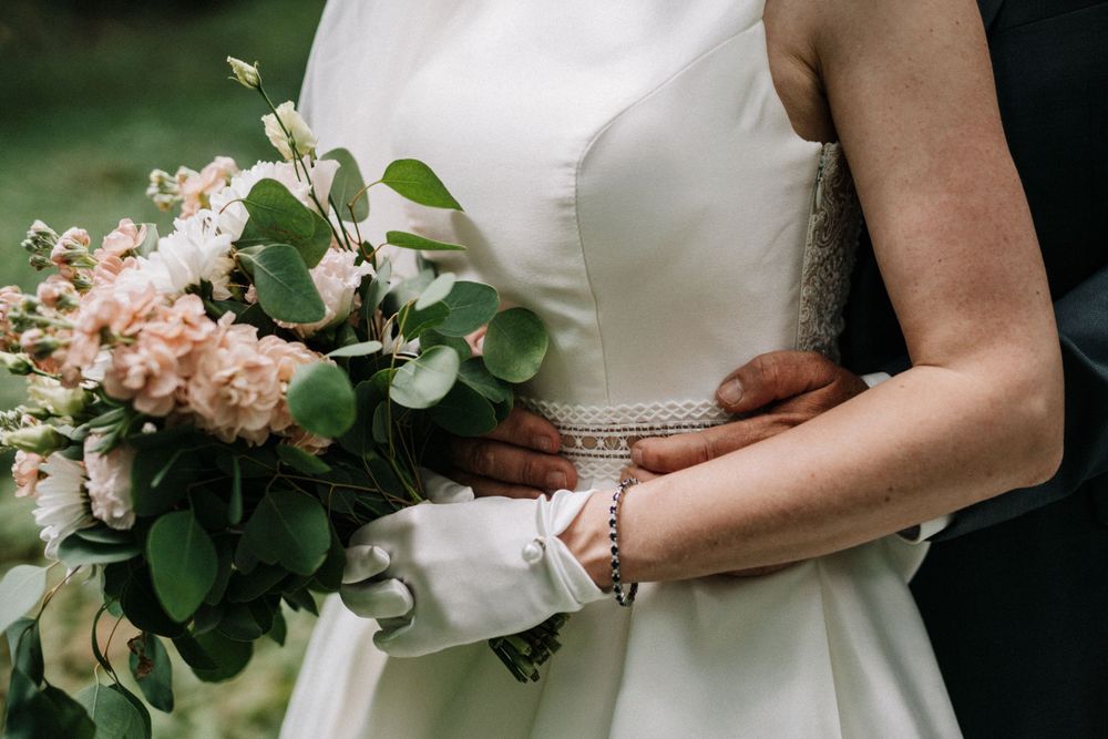 Close-up details of a bridal bouquet featuring peach-colored flowers and greenery.