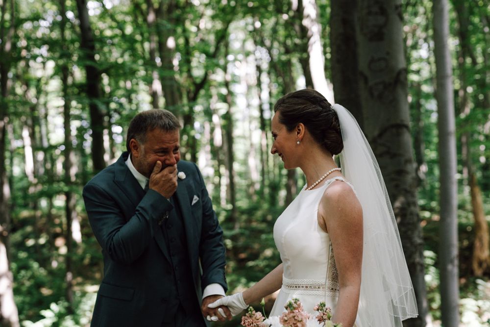 Tender wedding moments photographed among tall forest trees.