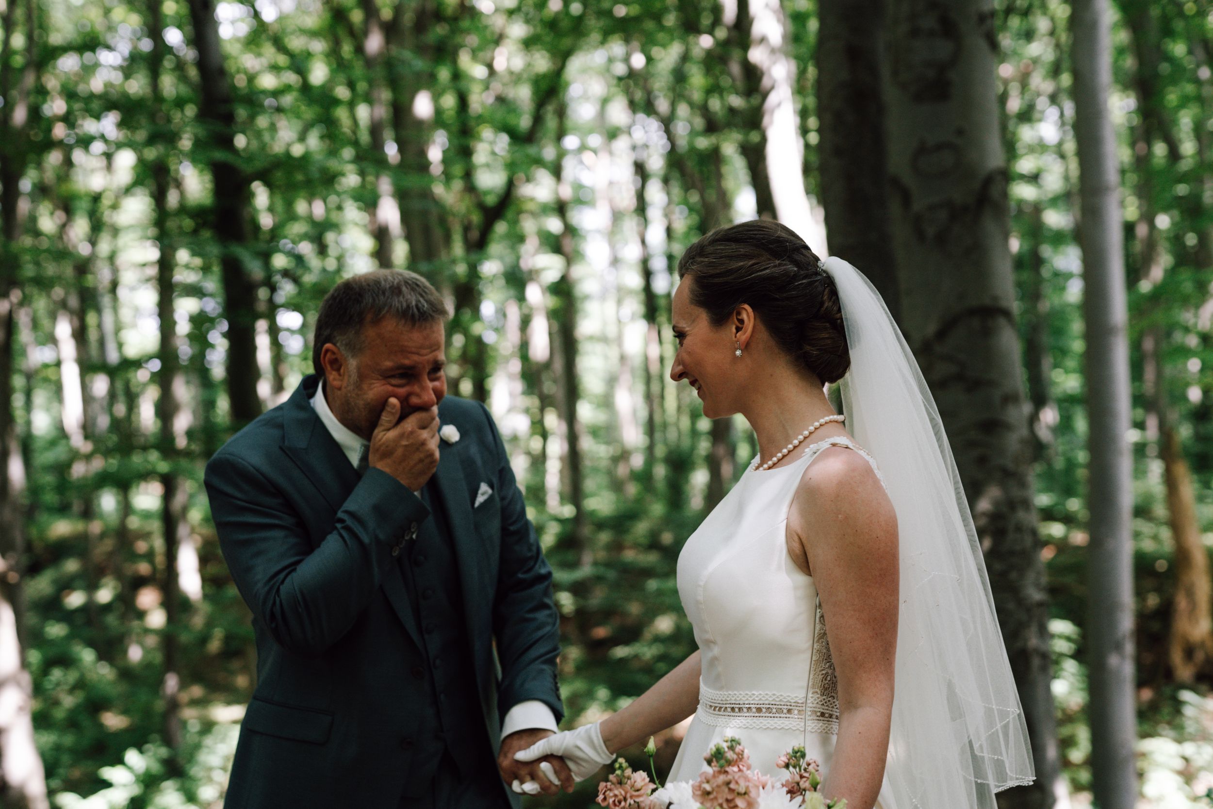 Tender wedding moments photographed among tall forest trees.