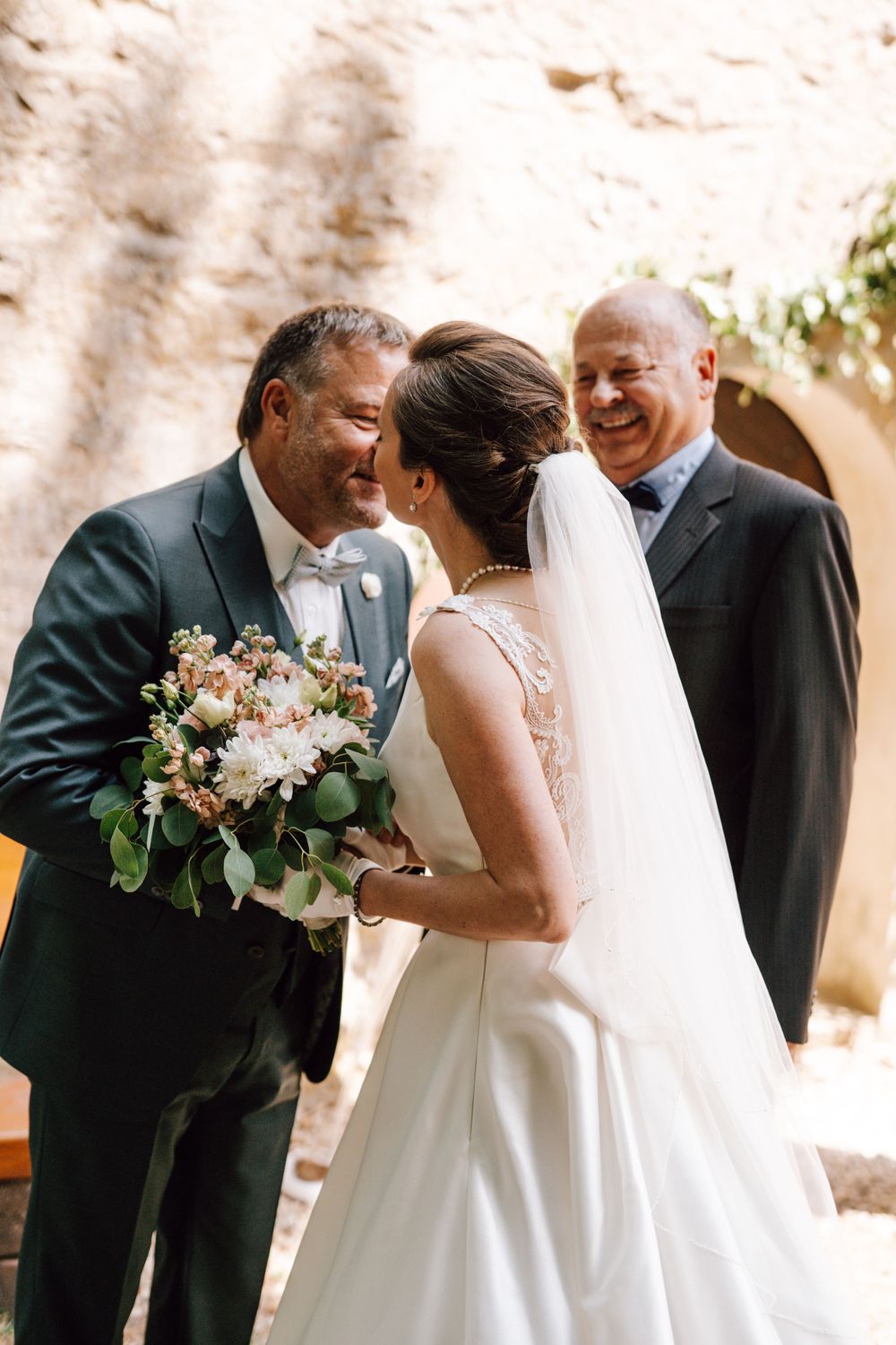 Wedding ceremony candid moment with floral bouquet and white dress.