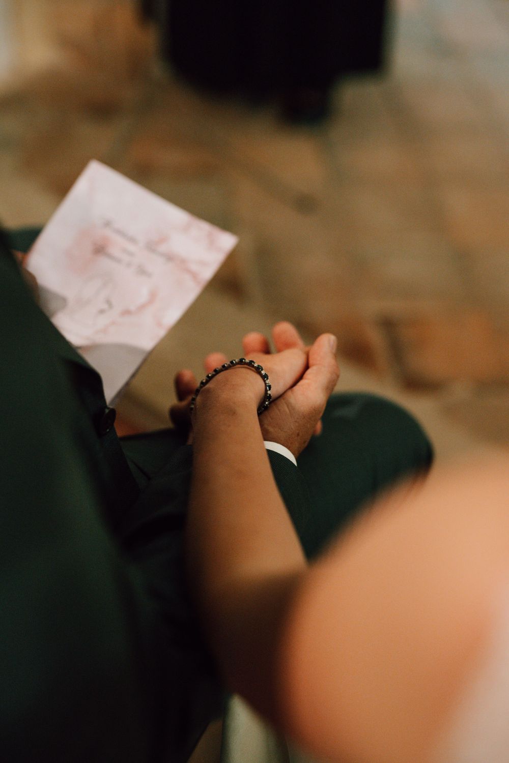 Close-up shot of hands writing on paper during a wedding ceremony.