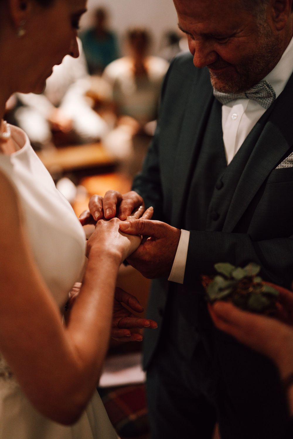 Close-up shot of hands exchanging wedding rings during an intimate ceremony.