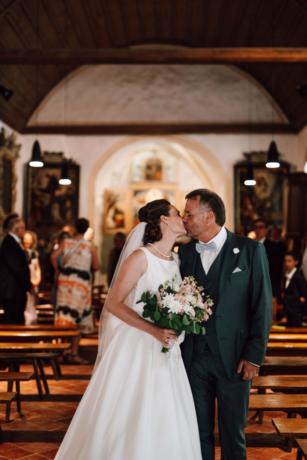 Romantic wedding moment captured in a traditional church setting with wooden pews.