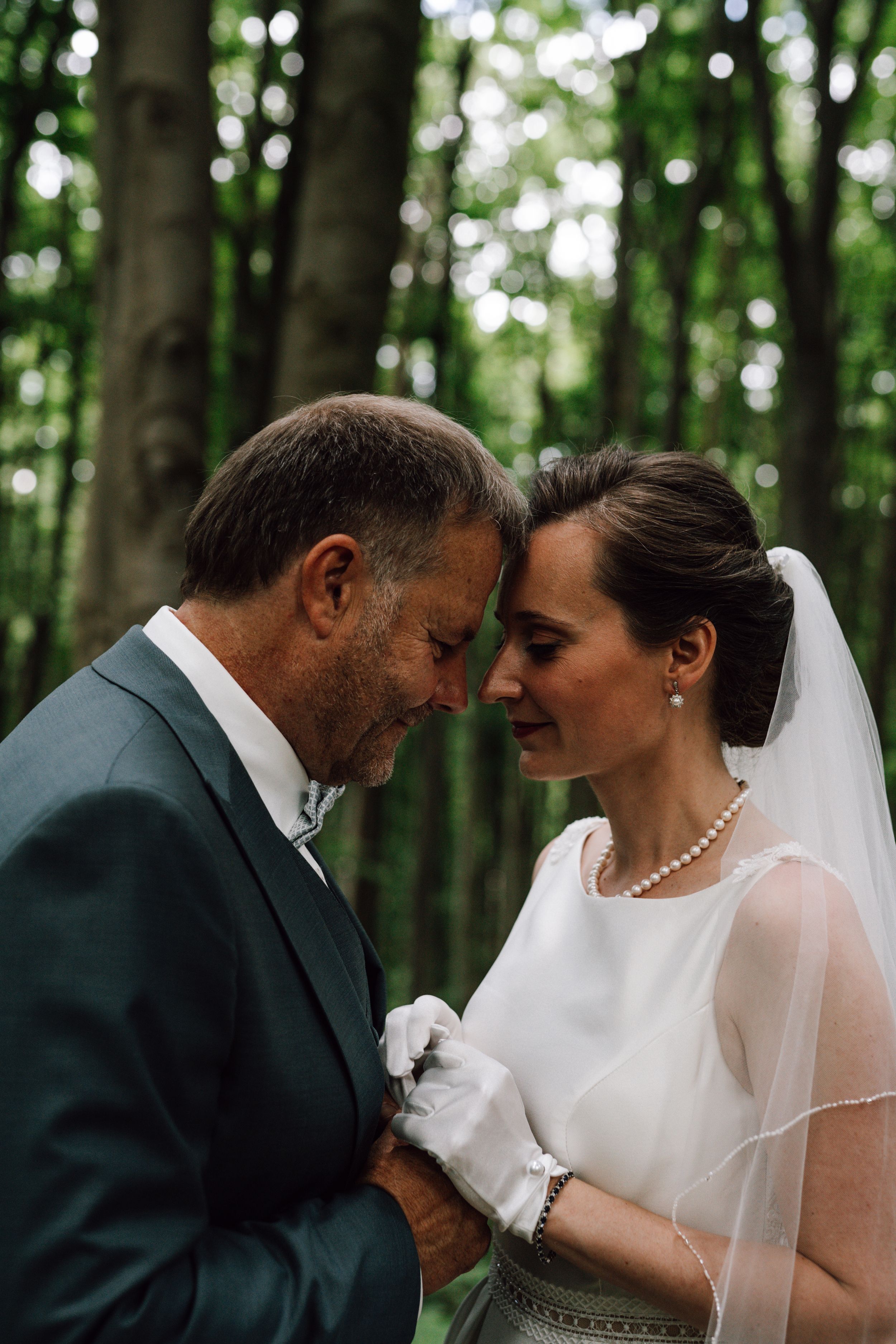 Intimate wedding portrait showing tender moment between couple in forest setting.