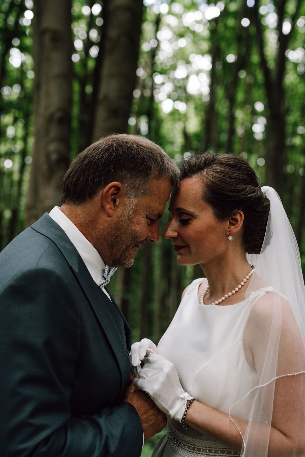 Intimate wedding portrait showing tender moment between couple in forest setting.