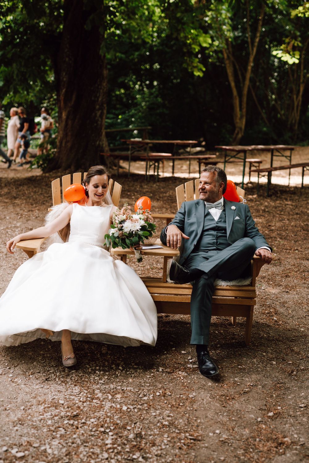 A couple relaxes on a wooden bench in a rustic outdoor setting.