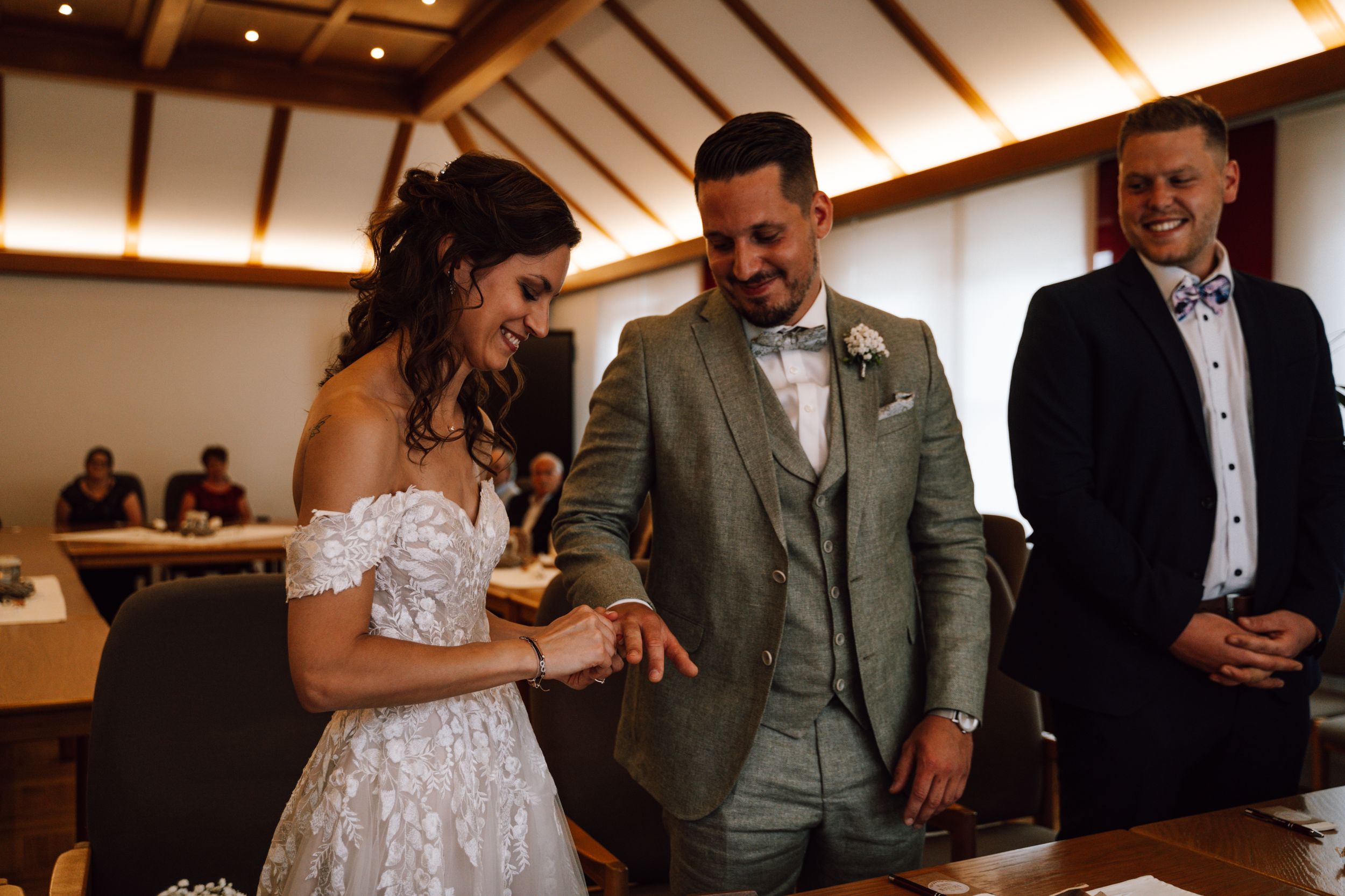 Wedding ceremony moment in a room with wooden beamed ceiling and warm lighting.