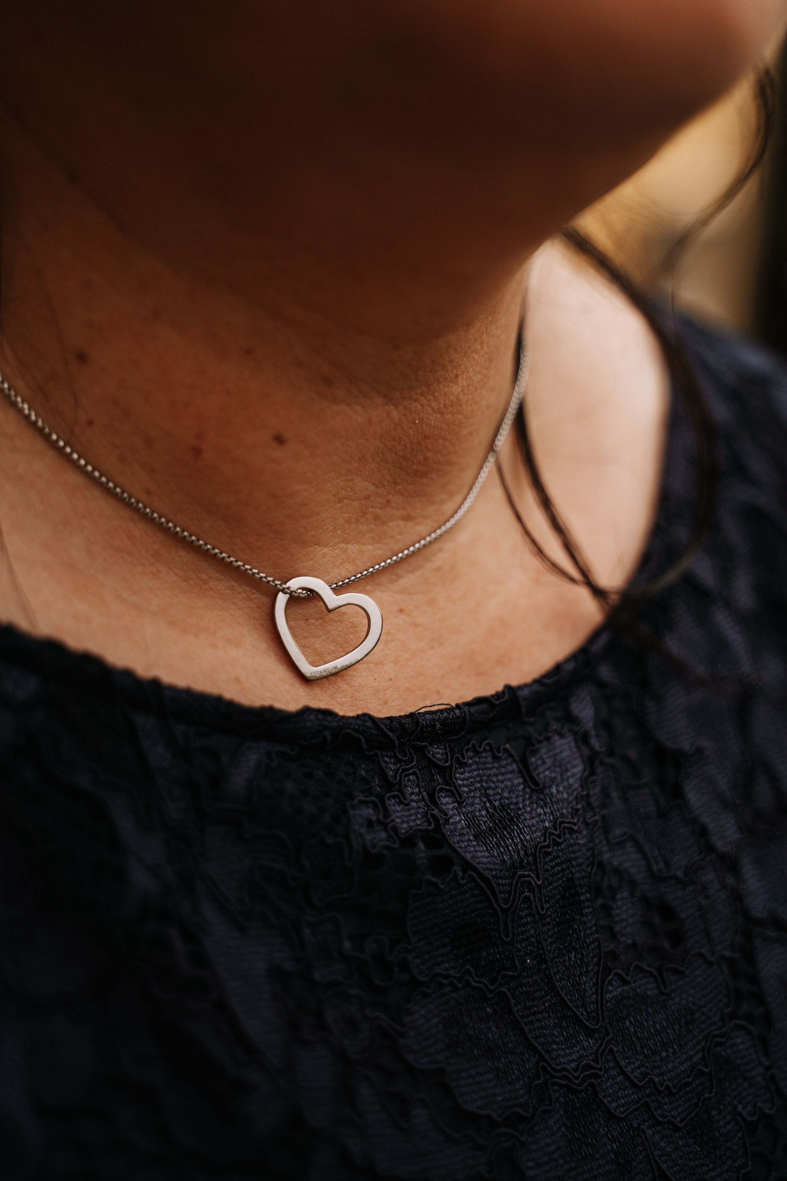 Silver heart pendant necklace on dark fabric.