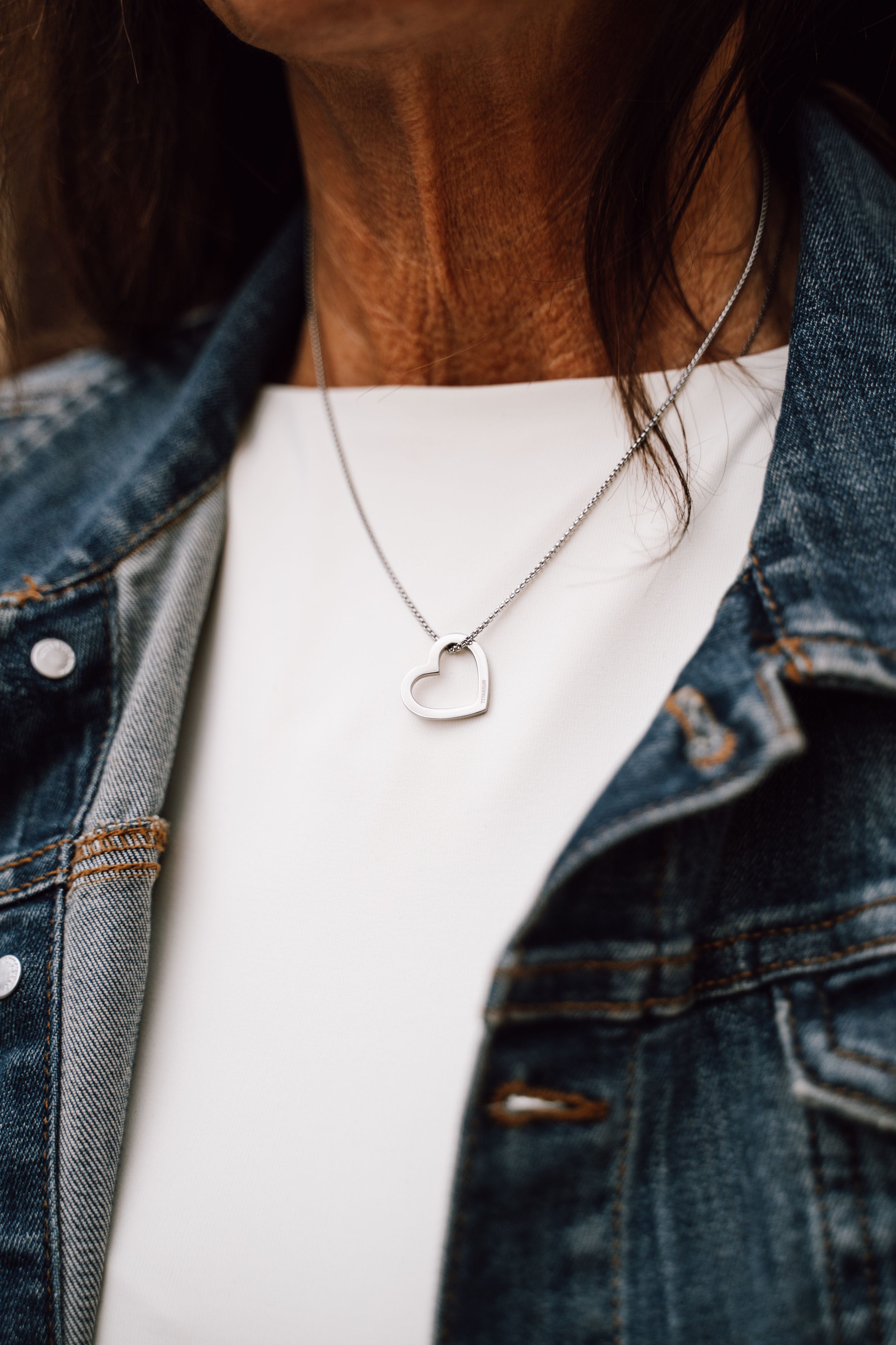 Delicate silver heart necklace worn with denim jacket.