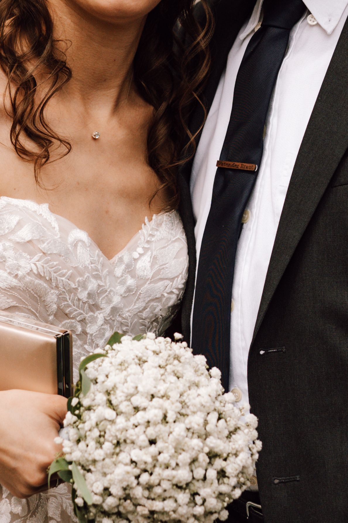 Wedding couple detail with white baby's breath bouquet and formal attire.