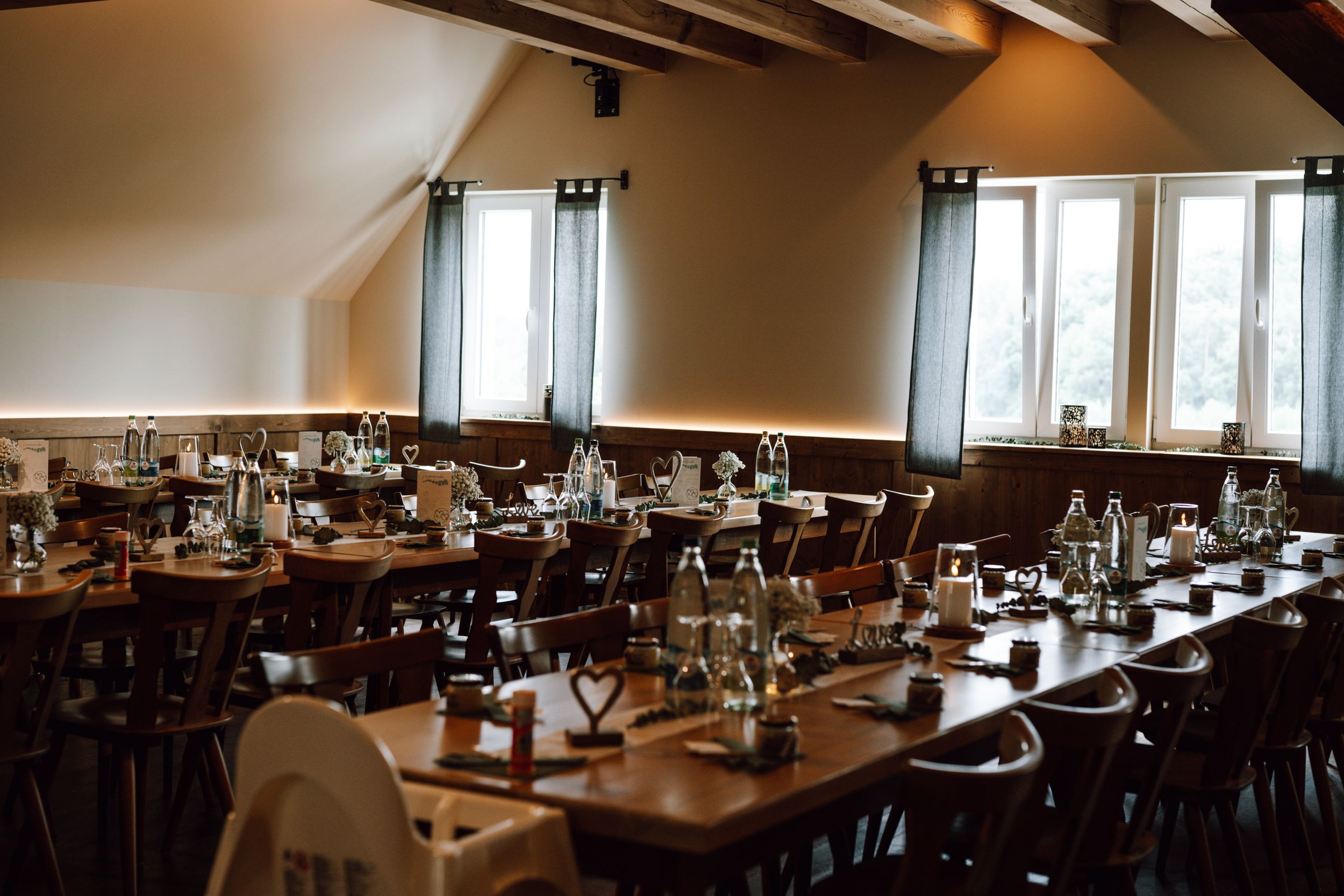 Wedding reception venue with wooden tables and chairs arranged in rows.