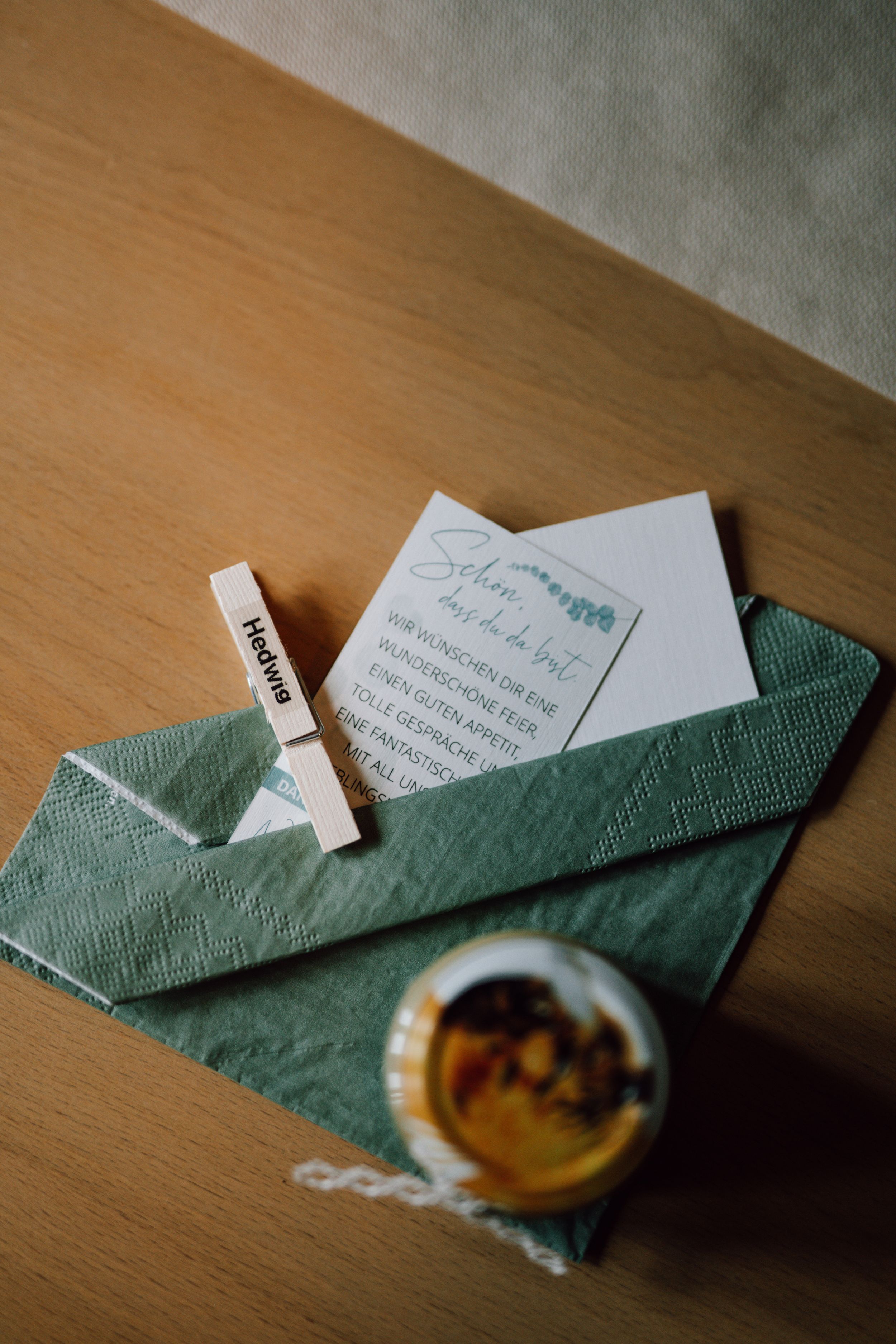 Green napkin folded with wedding cards on wooden surface.