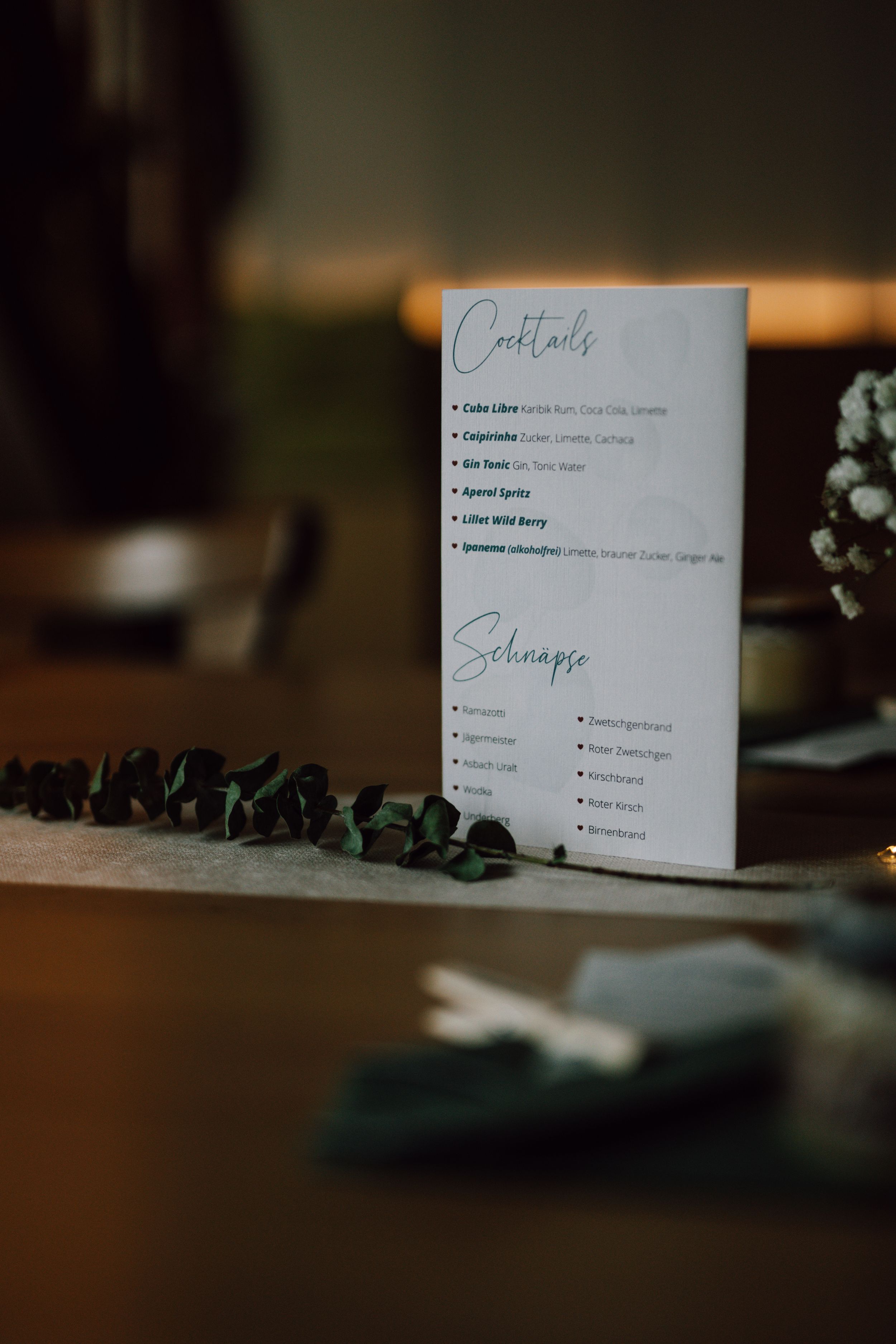 Wedding menu cards with greenery decoration on wooden table.