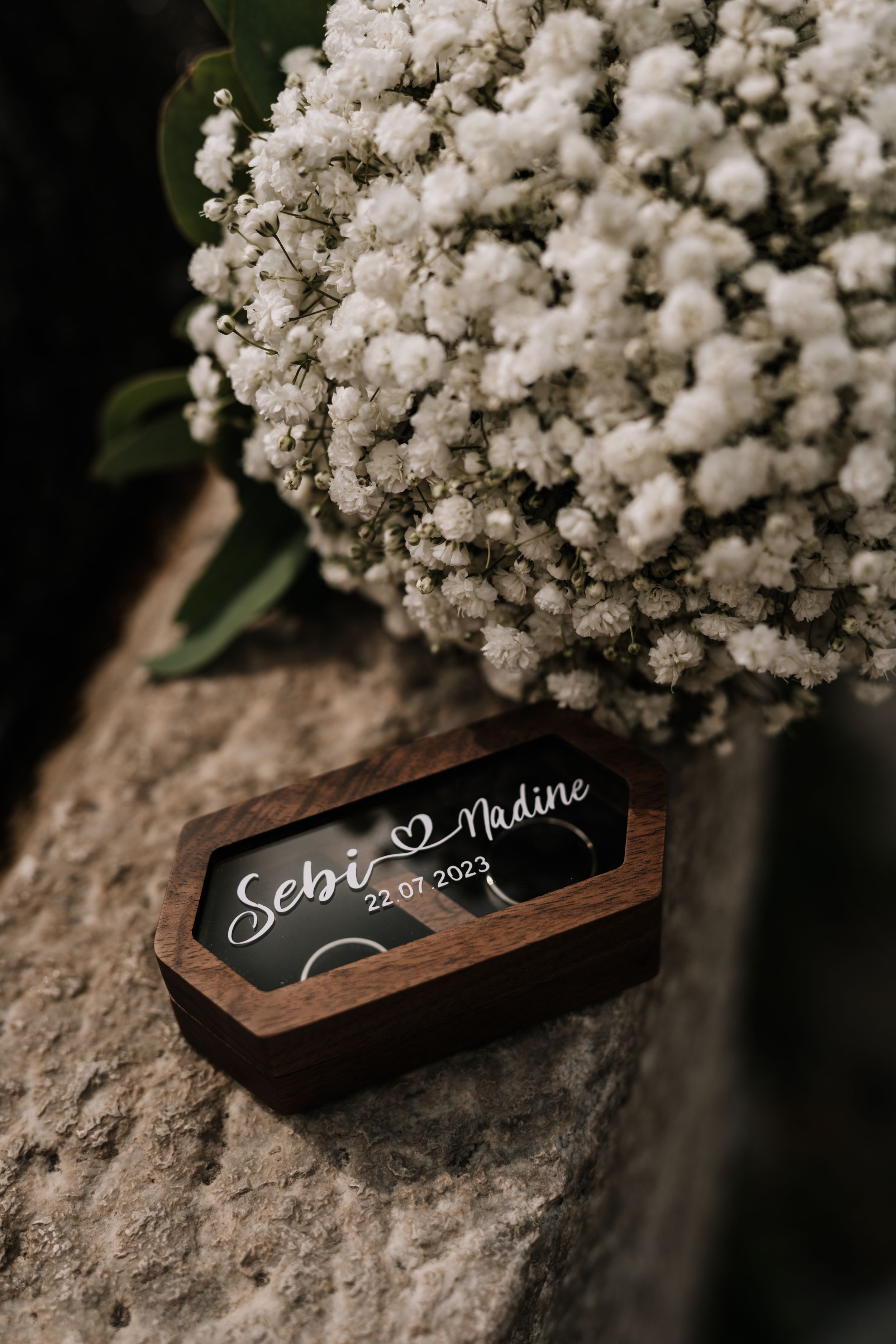 A wooden name plate with calligraphy sits beside delicate white baby's breath flowers.