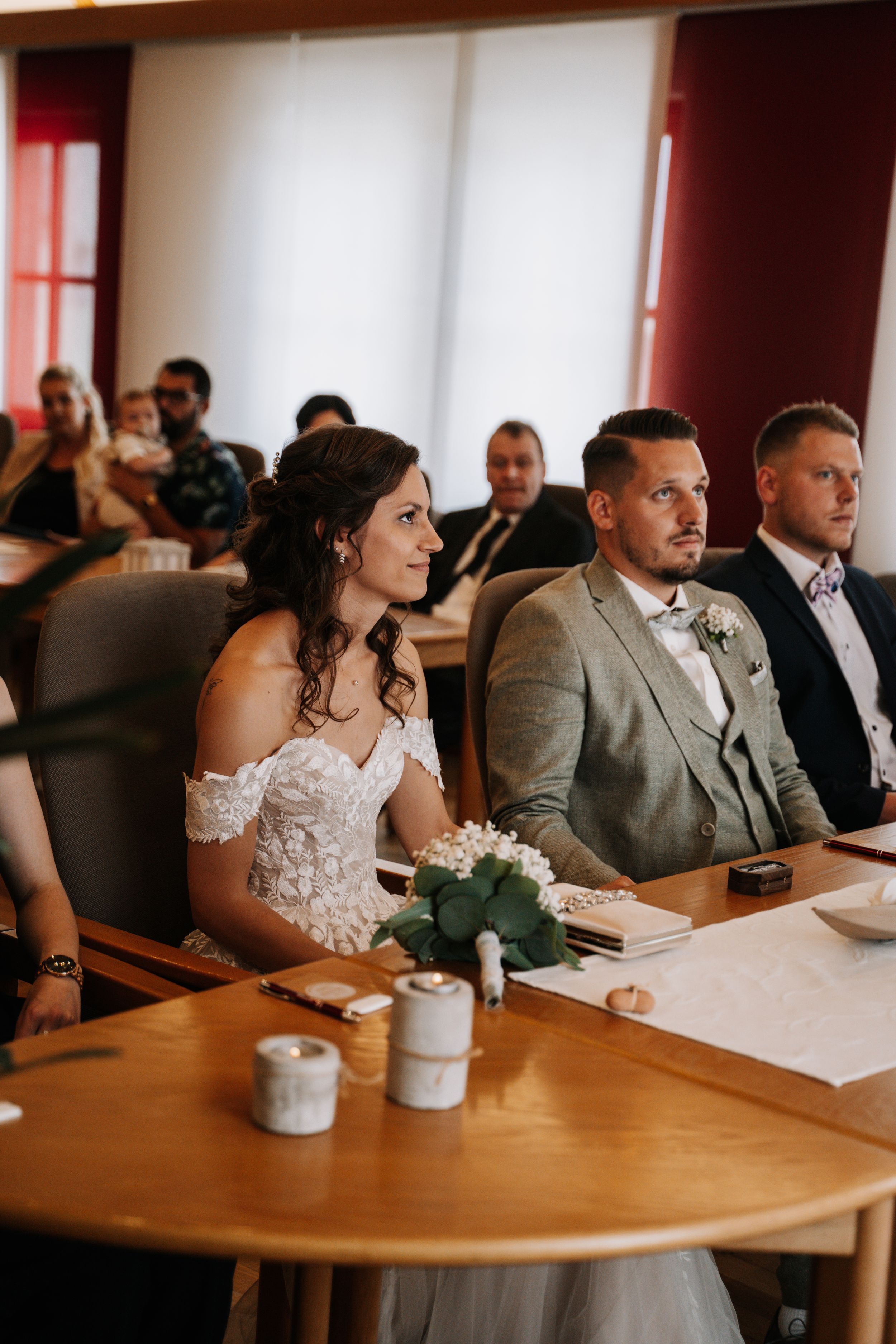 Wedding ceremony in a room with wood paneling and guests seated in rows.