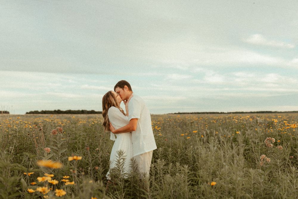 Couple embracing in golden field during sunset engagement session.