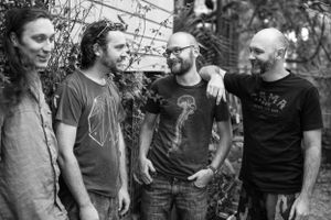 Black and white candid photo of four band members having a casual conversation.