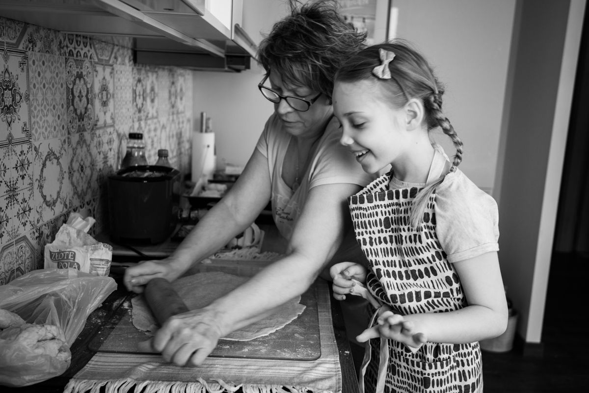 Black and white photo of parent and child baking together in kitchen.