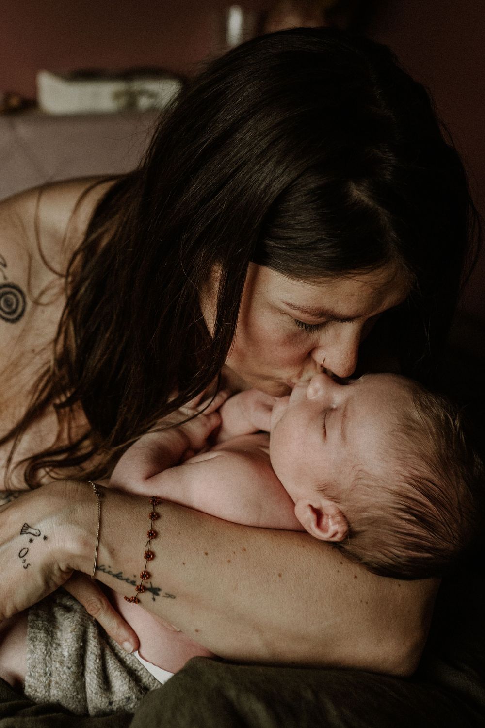 A tender moment between parent and newborn baby in warm, intimate lighting.