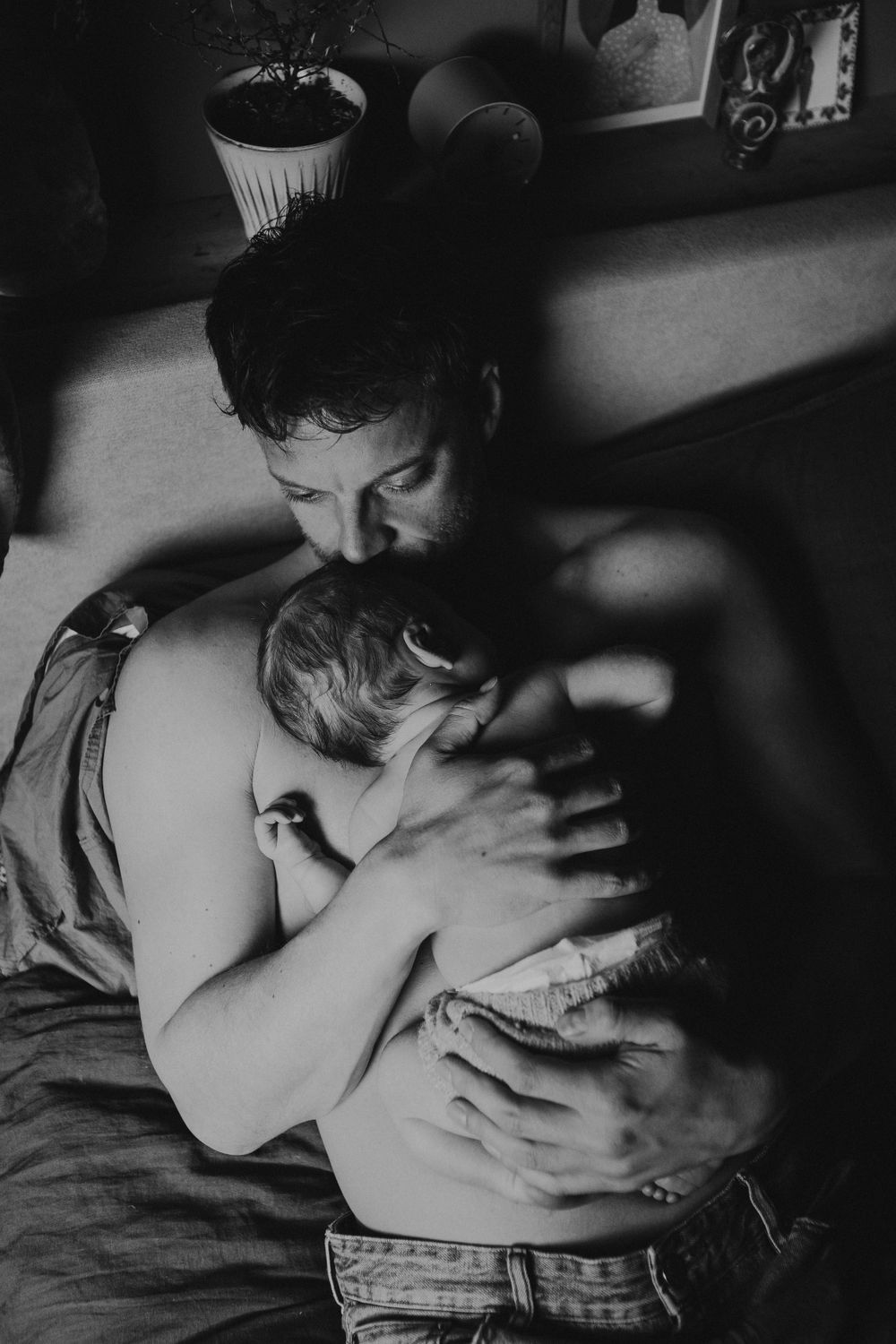 An intimate black and white portrait of new parents holding their newborn baby.