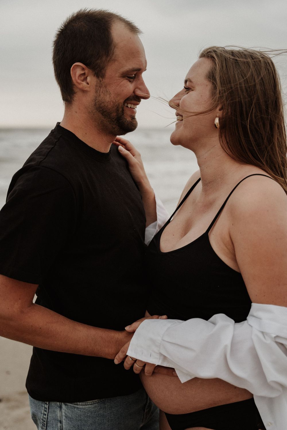 An intimate moment between a couple on the beach during their maternity photo session.