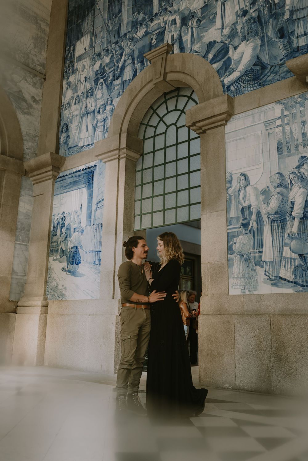 Couple sharing romantic moment in historic building with blue tile murals.