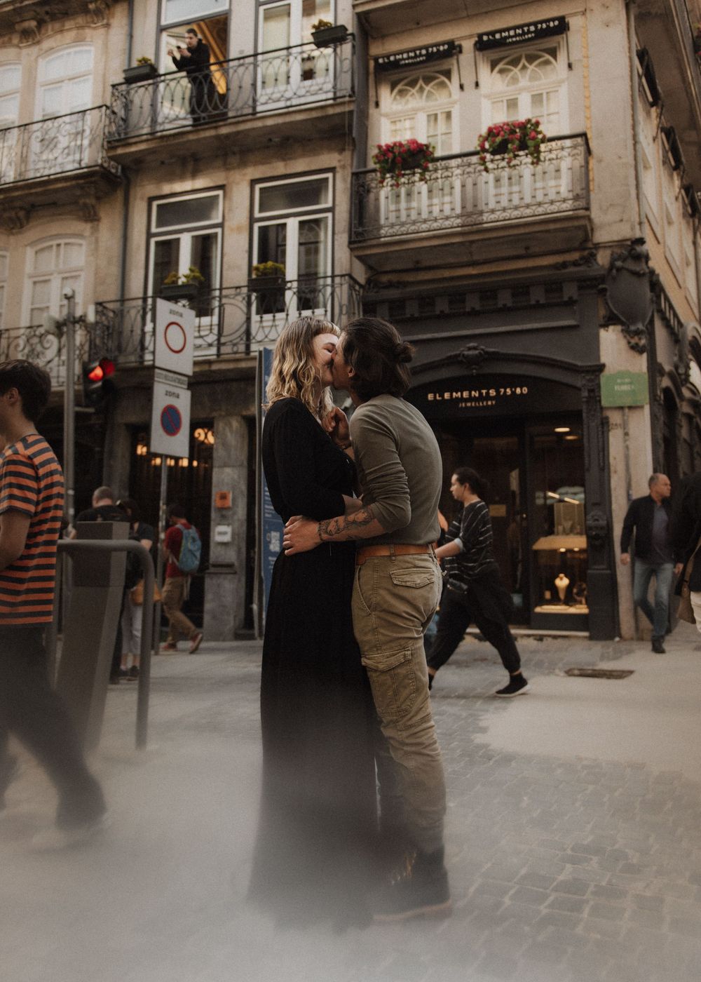 Romantic embrace on a European city street with vintage architecture and balconies.