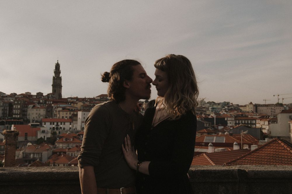 A couple sharing a tender moment on a rooftop while overlooking the terracotta roofs and buildings of Porto.