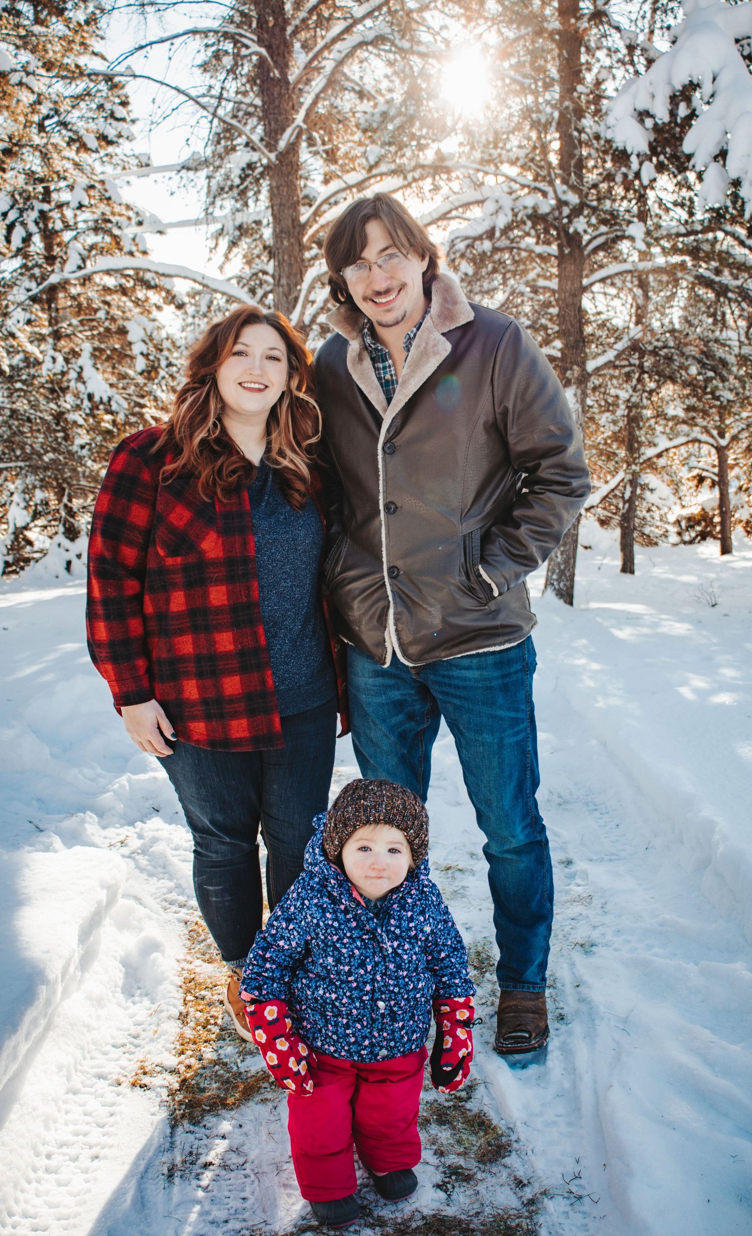 A family of four walking together in a sunlit field during golden hour.