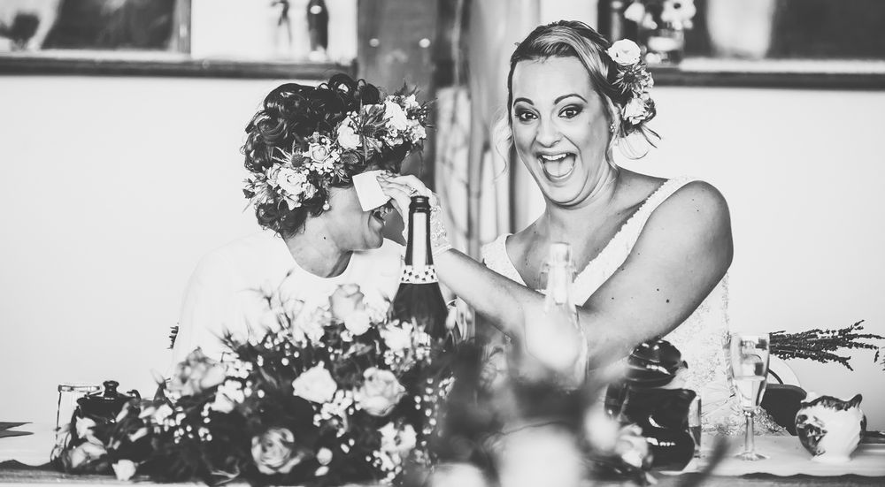 A woman wipes away tears from her wife at the wedding speech while both laughing