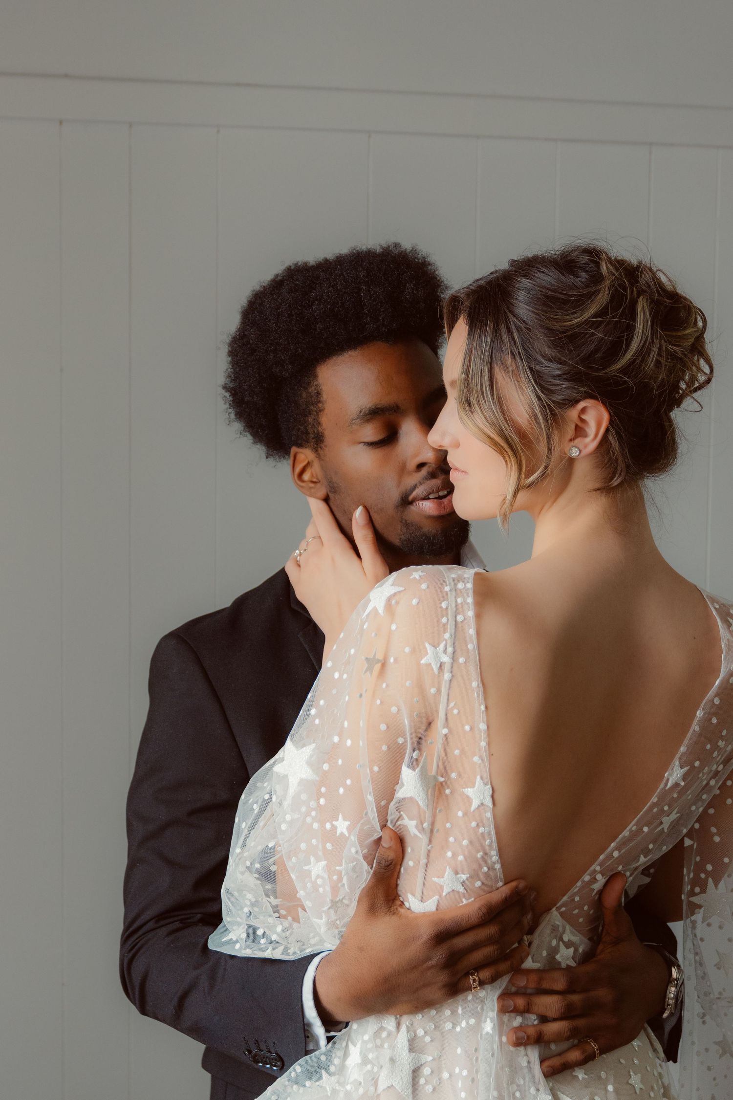 Intimate wedding portrait of couple sharing tender moment in white lace dress and dark suit.