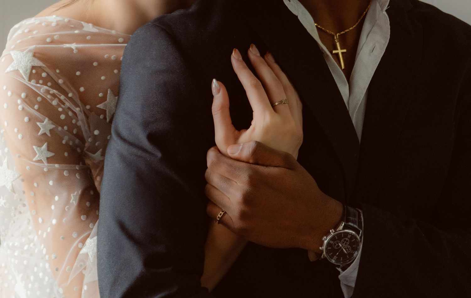 Close-up detail of couple's hands and formal attire during intimate wedding moment.