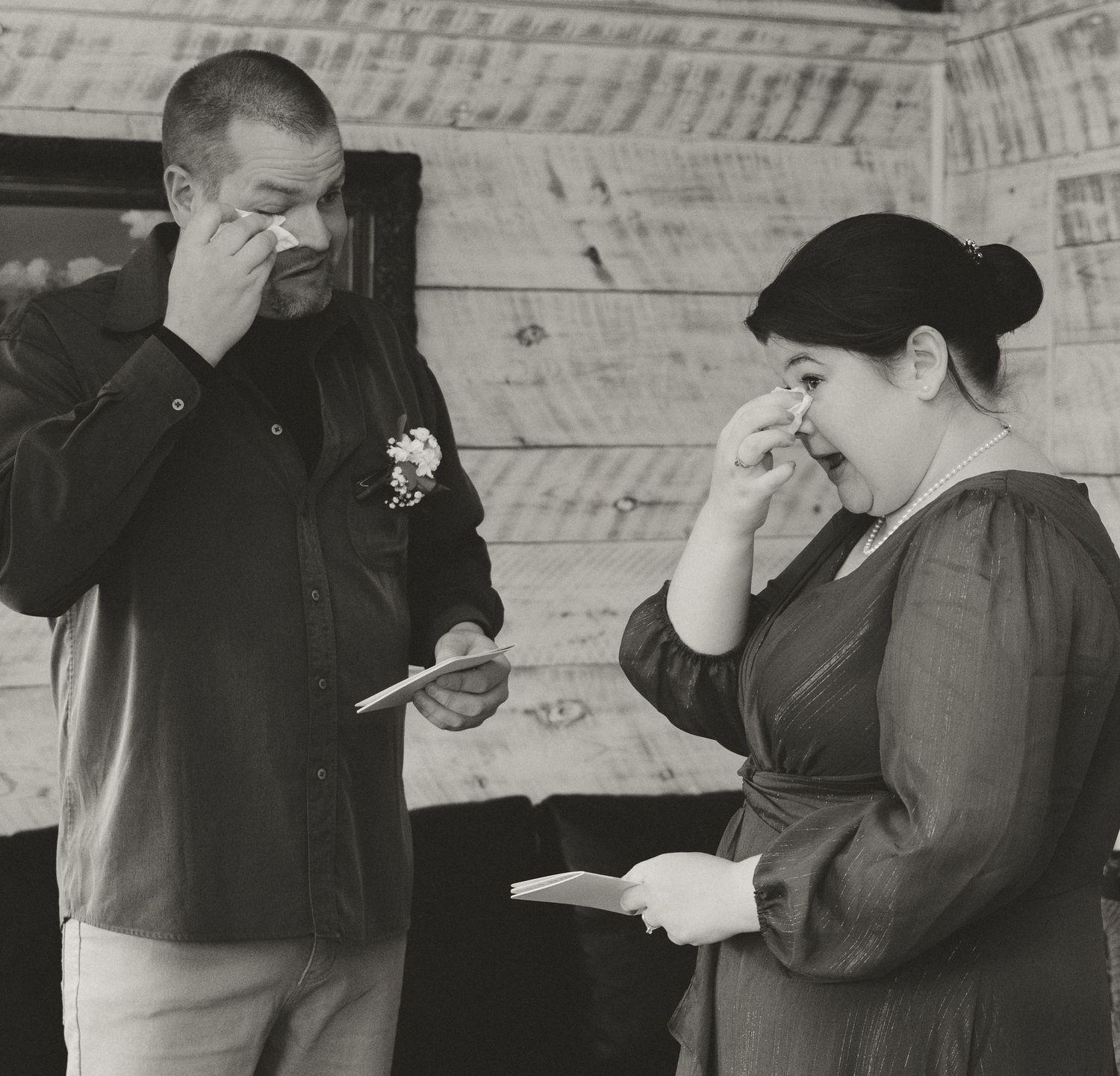 Two people wipe tears during an emotional ceremony moment.