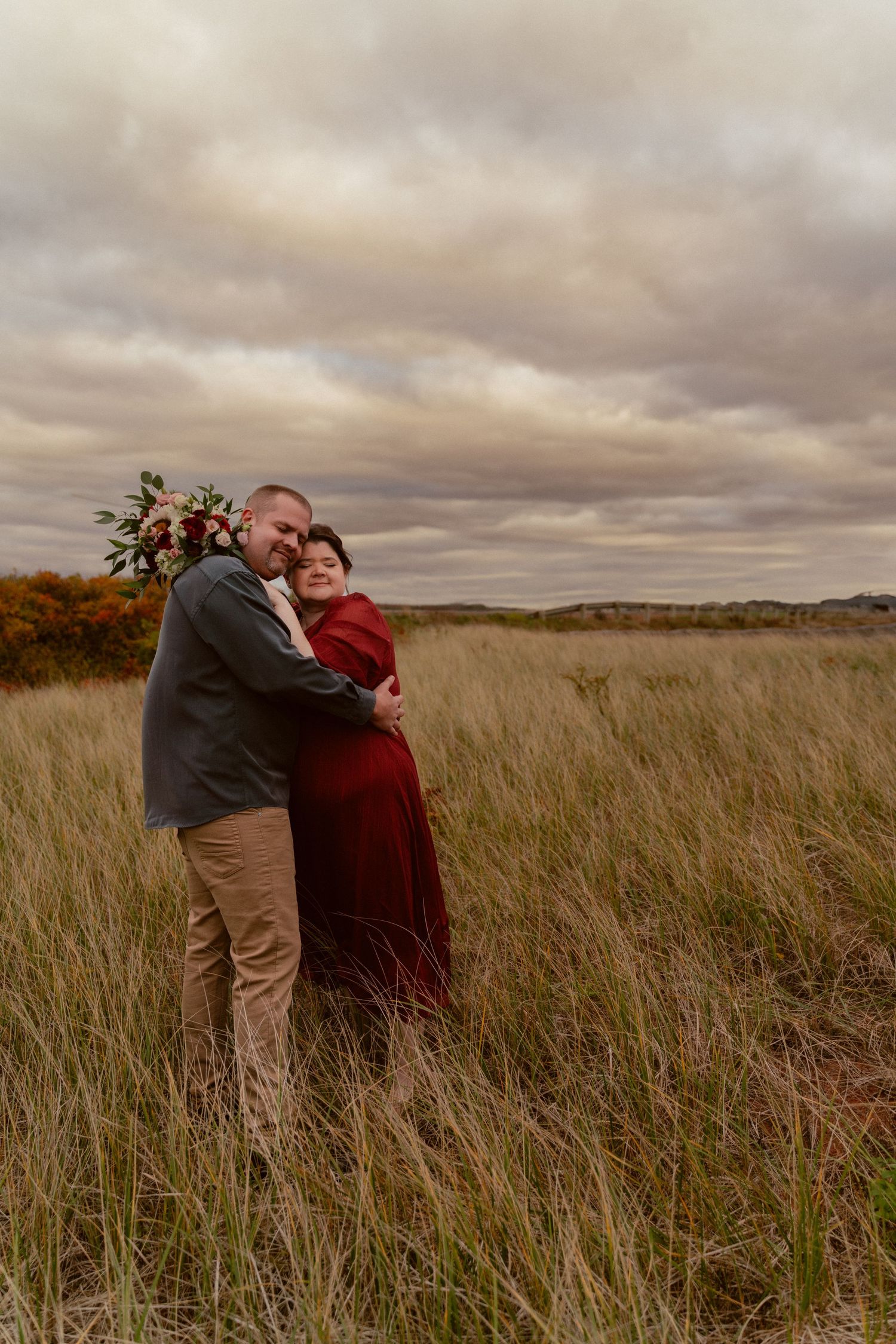 A romantic embrace in tall grass under moody autumn skies.