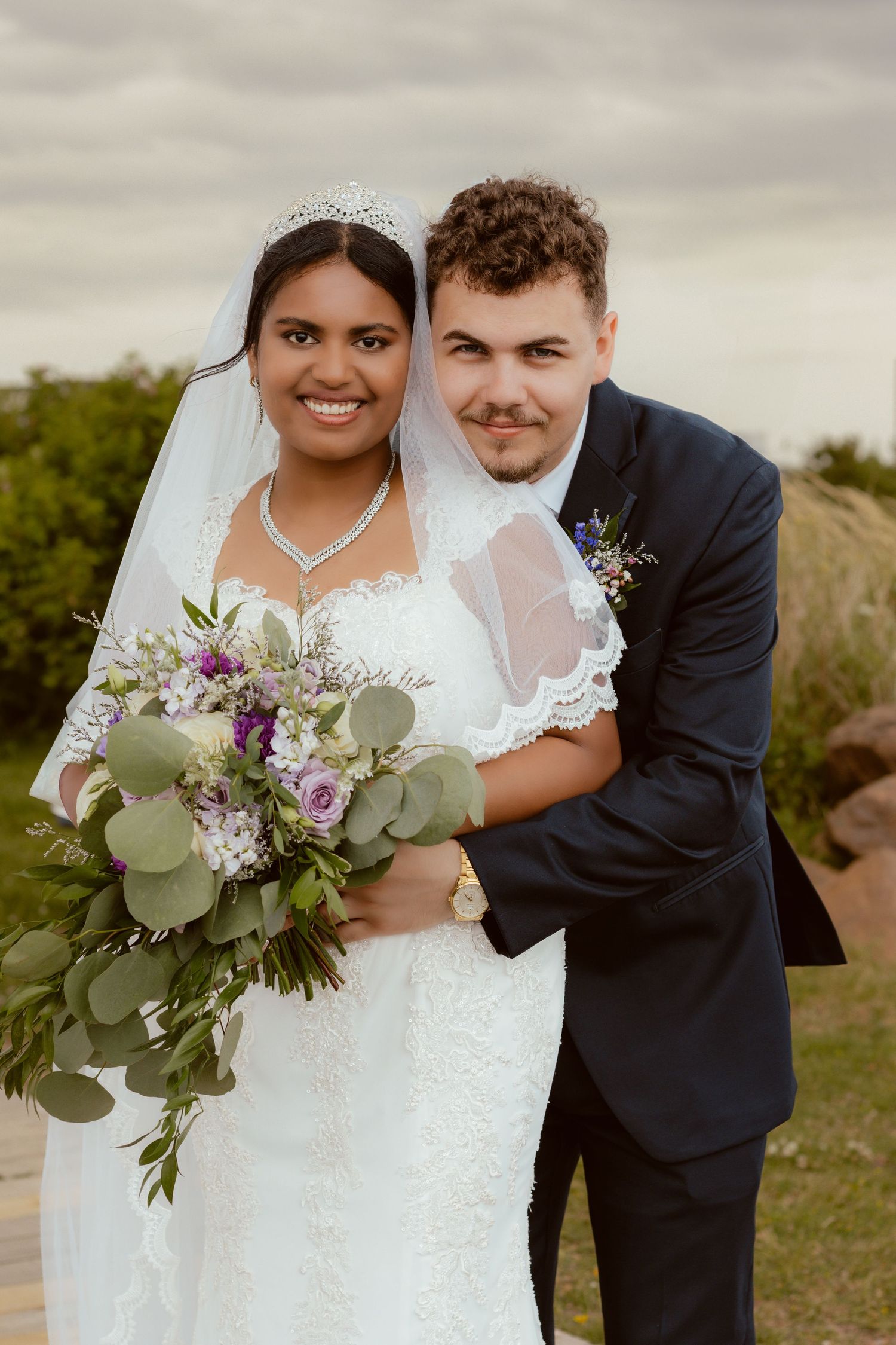 A romantic wedding portrait featuring a beautiful bouquet with eucalyptus and purple flowers.