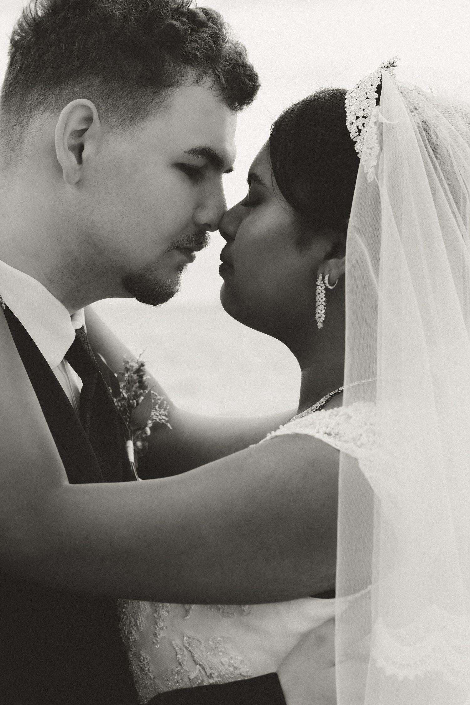 A romantic black and white close-up of a bride and groom sharing an intimate moment on their wedding day.