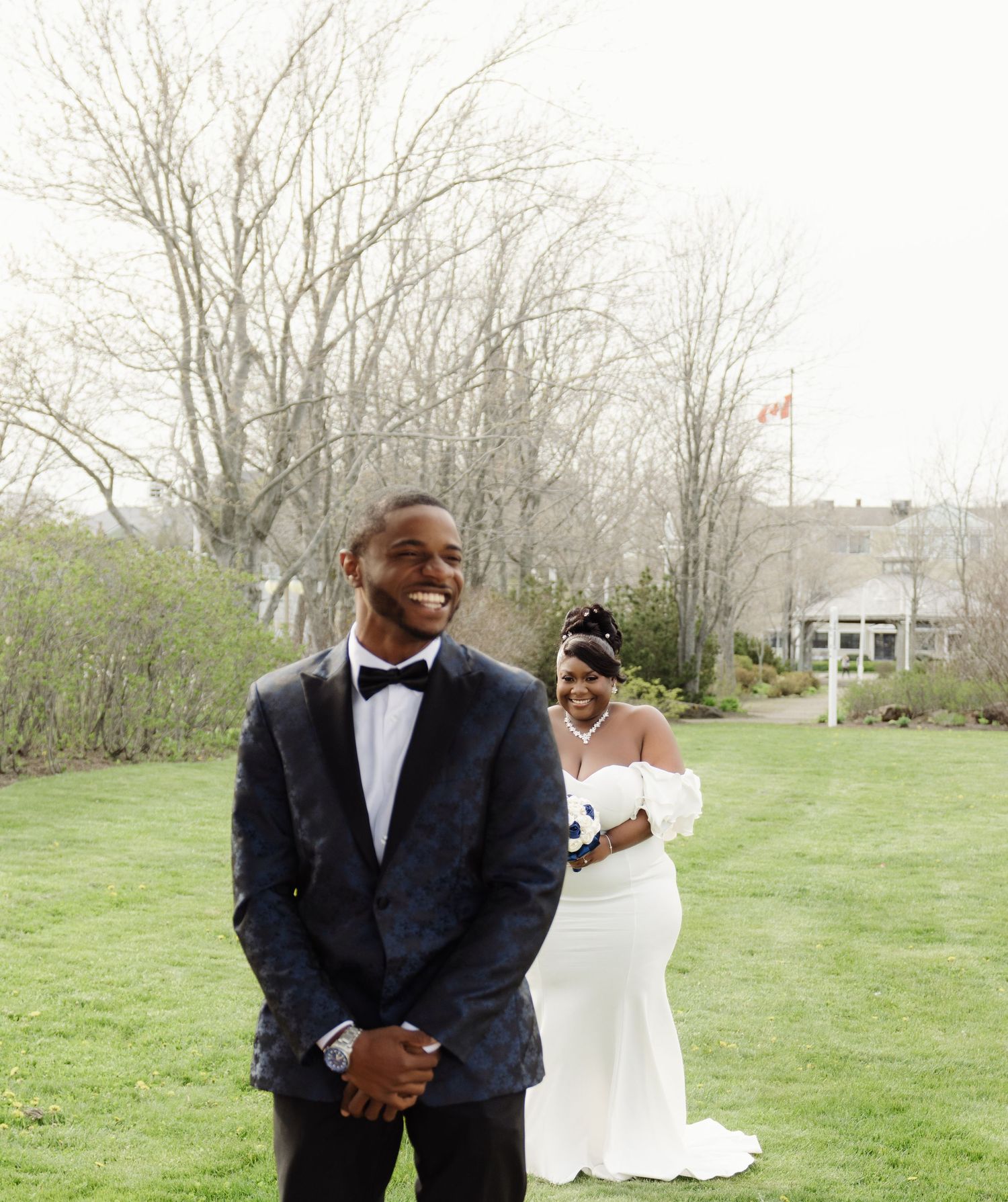 A joyful wedding portrait taken outdoors with a couple in formal attire against a spring background.