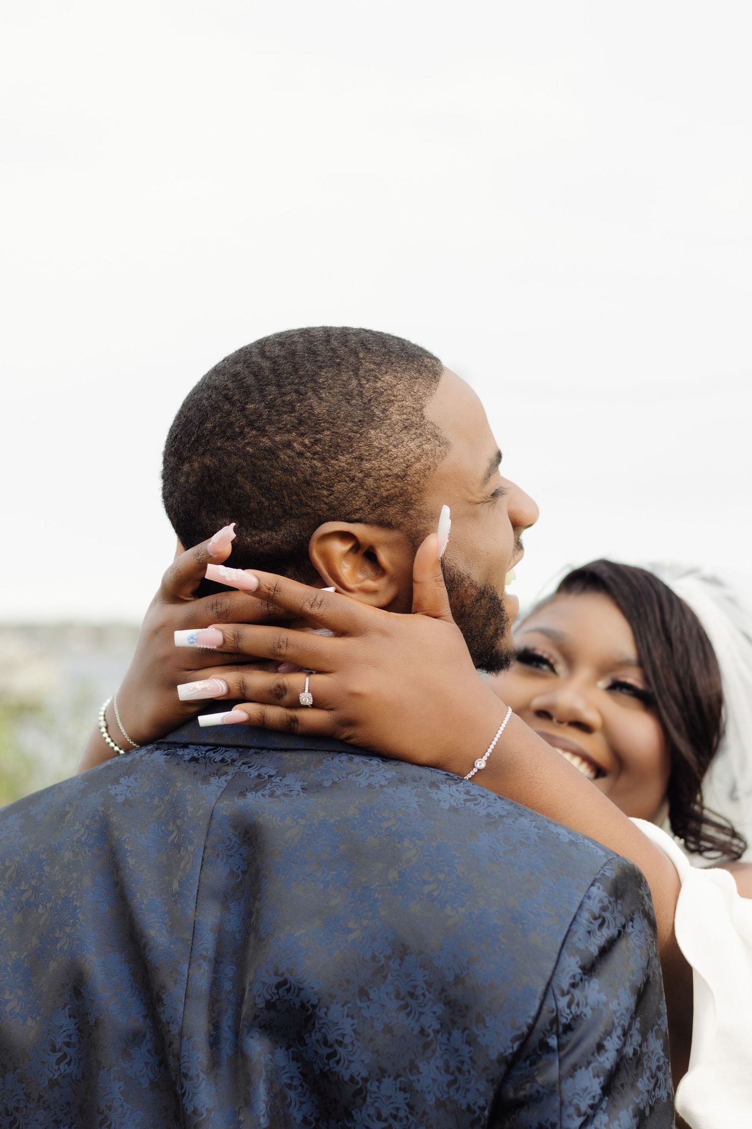 A tender embrace between newlyweds with the bride's hands gently holding her partner's face.