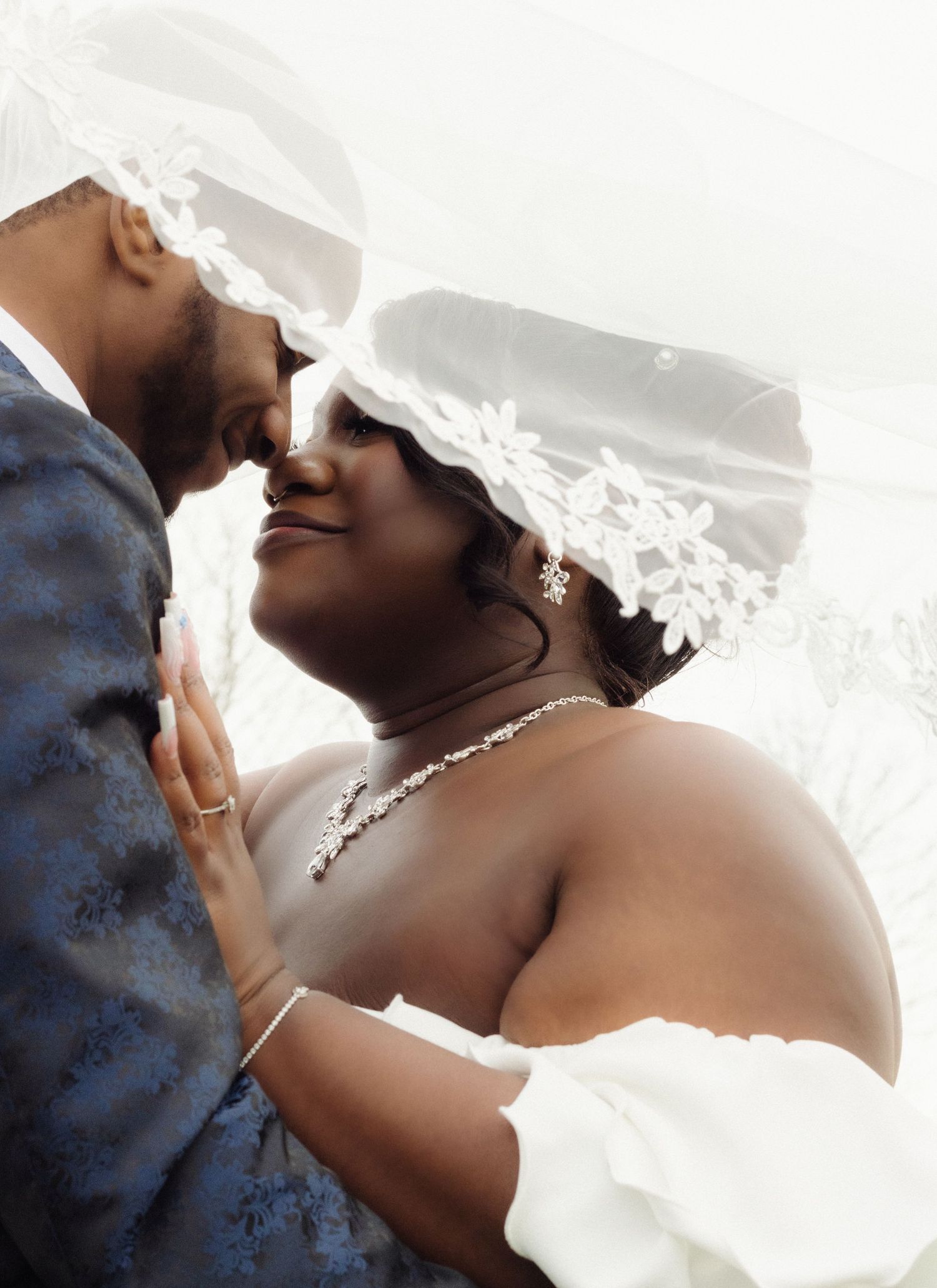An intimate wedding portrait showing a tender moment between newlyweds under a delicate veil.
