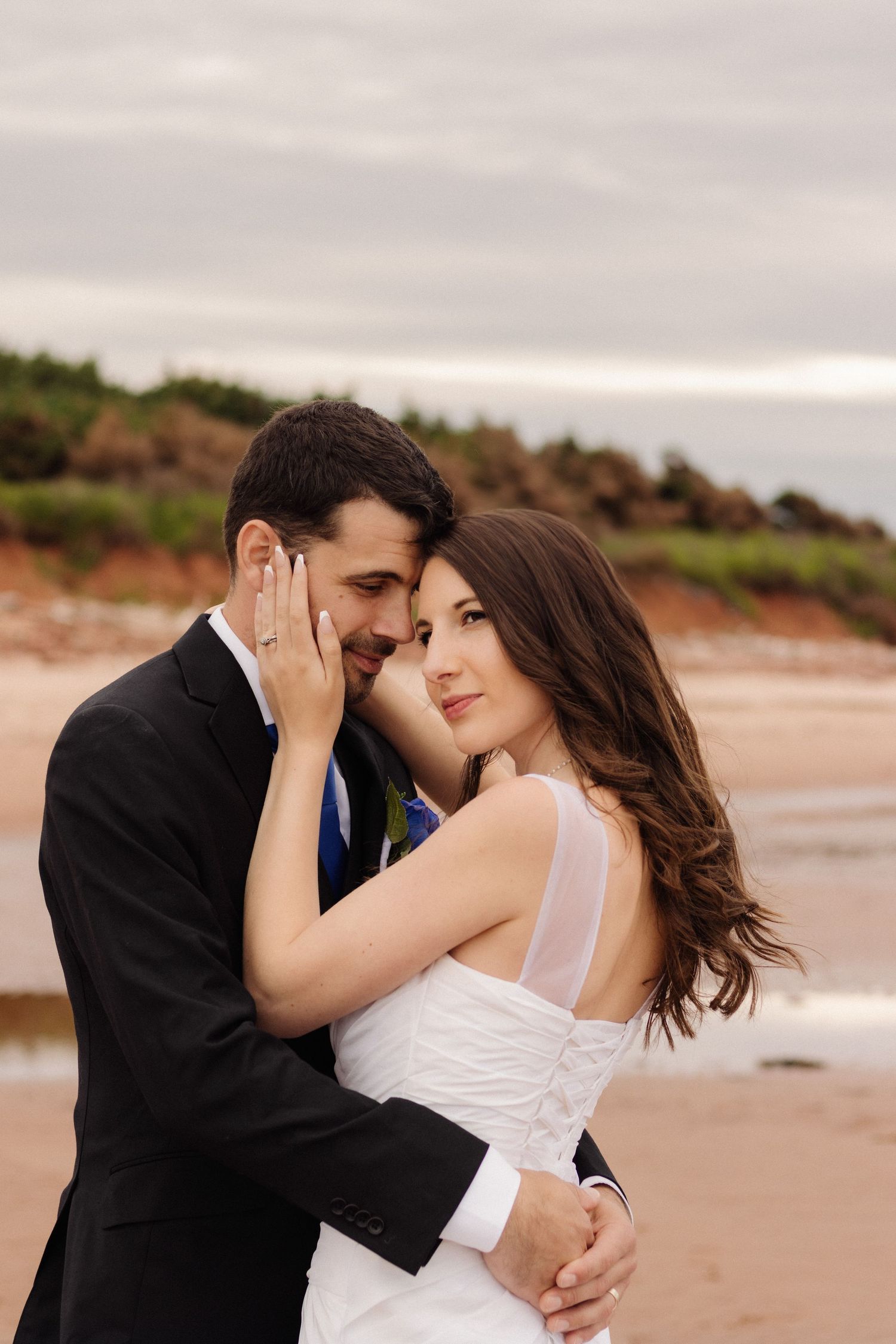 An intimate portrait of a couple embracing on a beach during golden hour.