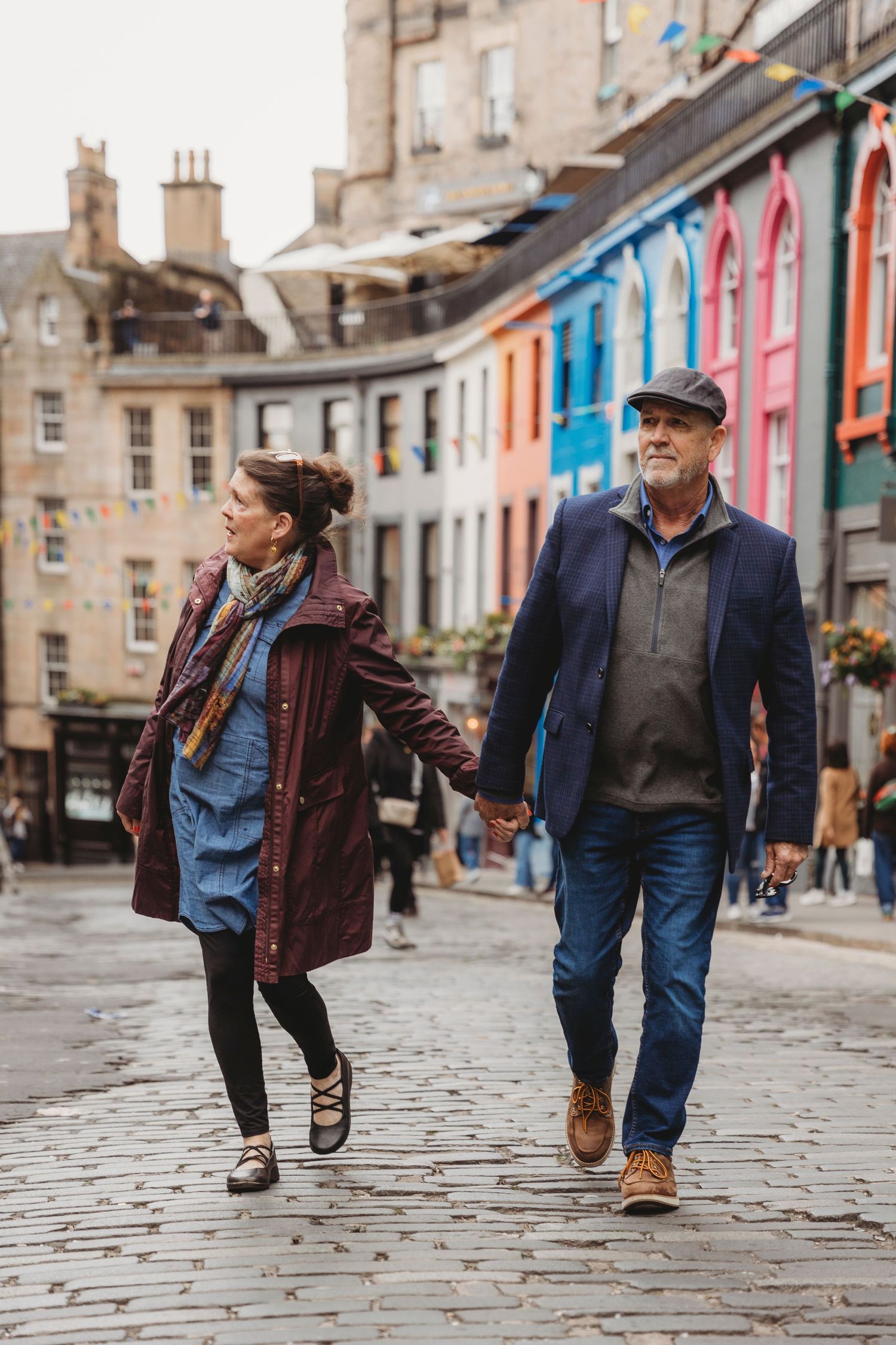 A couple strolling down a colorful street in Edinburgh's historic district.