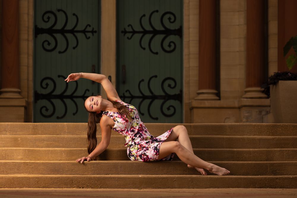 Artistic portrait of dancer posing gracefully on stone steps at sunset.