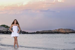 High school senior girl on beach at sunset with cotton candy skies at Wingaersheek