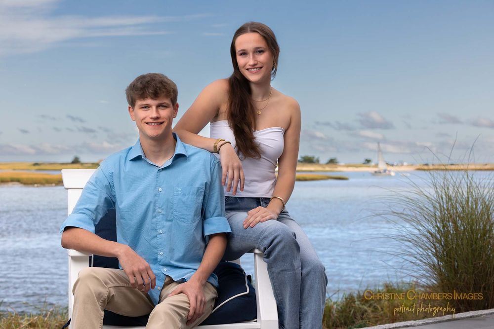 Twin siblings pose for casual outdoor portraits near the ocean and beach grass on a sunny day. High school senior boy and girl
