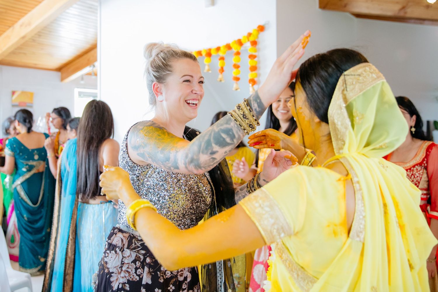 Haldi ceremony from Indian wedding with Bride having turmeric applied by friend