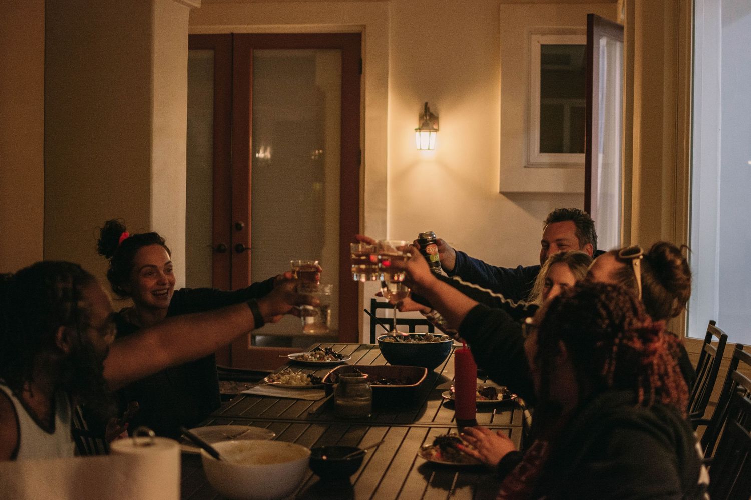 A group of friends raising glasses for a toast during a dinner gathering.