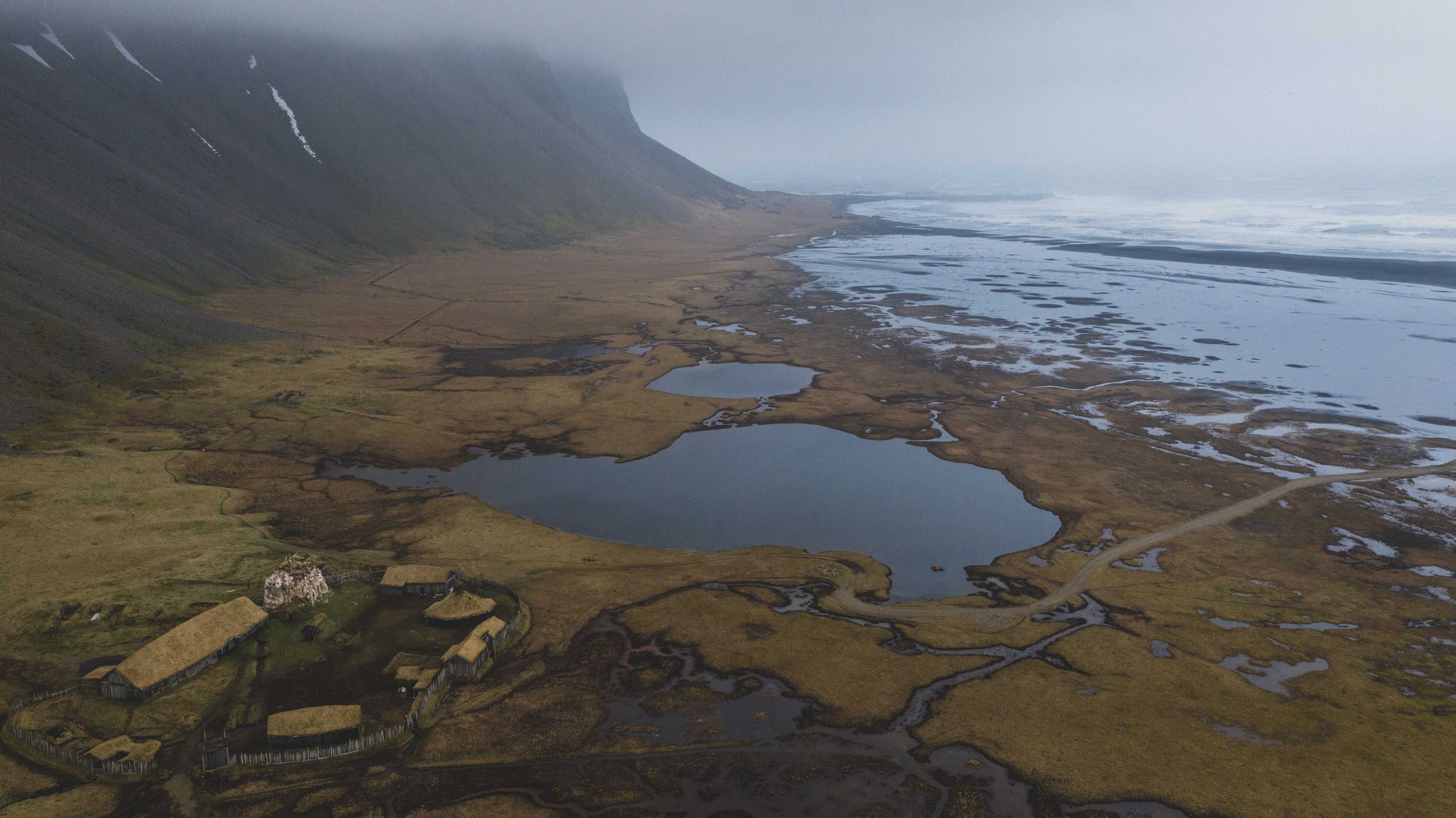 Aerial view of coastal wetlands and lagoons nestled between mountains and ocean.