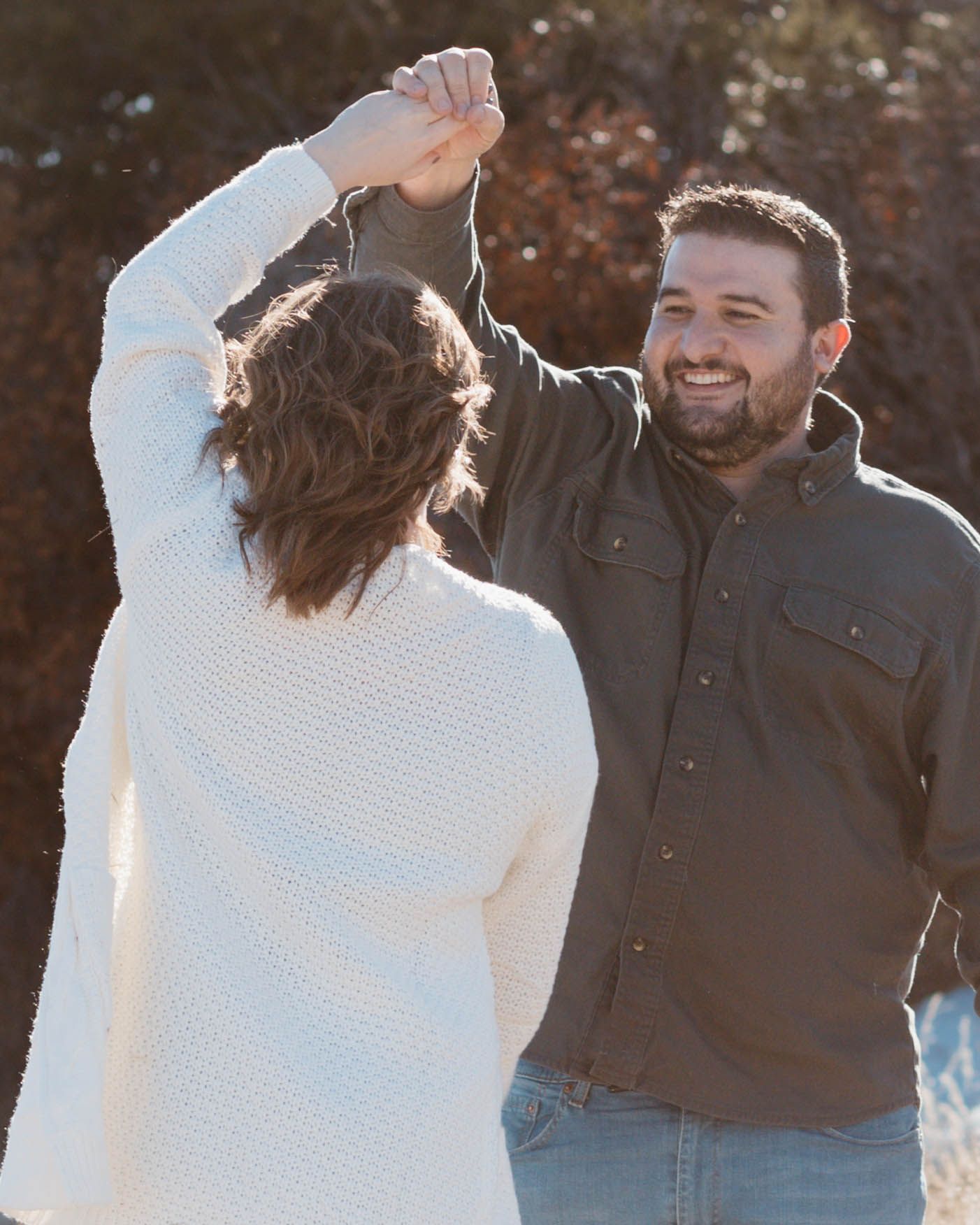 A couple dancing together outdoors with sunlight behind them.